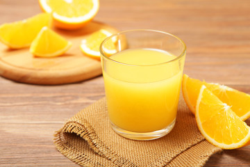 Orange juice in a glass, oranges and orange slices on the table.