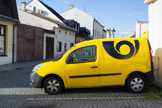 Karvina, Czech Republic / Czechia - May 19, 2019: Yellow auto, car and vehicle with sign - Logo and symbol of postal service in Czechia ( Ceska posta, Czech post ). Street out of focus in distance