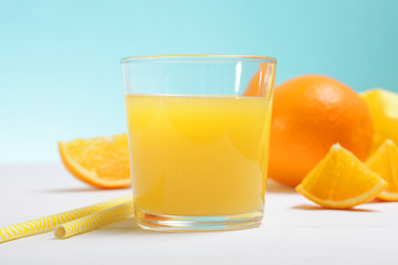 Orange juice in a glass, oranges and orange slices on the table.