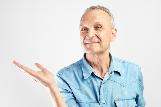 Positive Gray-haired Grandfather Smile Pretending To Be Holding Something In Palm Of Hand In White Studio Isolated With Copy Space