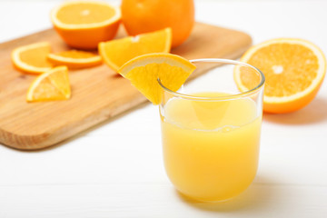 Orange juice in a glass, oranges and orange slices on the table.
