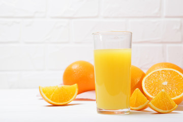 Orange juice in a glass, oranges and orange slices on the table.