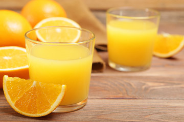 Orange juice in a glass, oranges and orange slices on the table.
