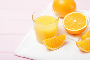 Orange juice in a glass, oranges and orange slices on the table.