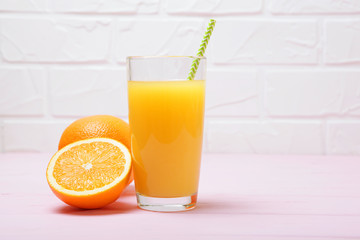 Orange juice in a glass, oranges and orange slices on the table.