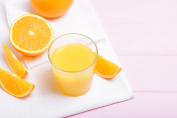 Orange juice in a glass, oranges and orange slices on the table.