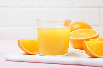Orange juice in a glass, oranges and orange slices on the table.
