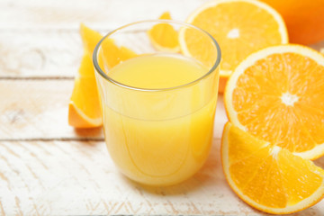Orange juice in a glass, oranges and orange slices on the table.
