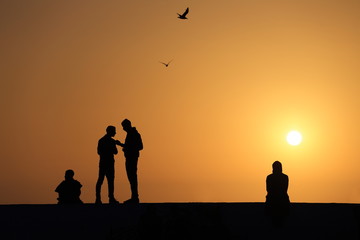Silhouettes of people at sunset on the beach - 297594615