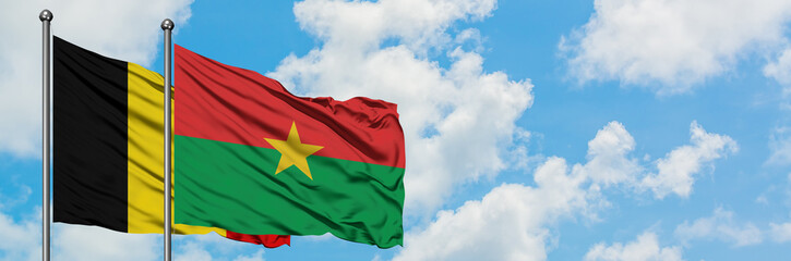 Naklejka premium Belgium and Burkina Faso flag waving in the wind against white cloudy blue sky together. Diplomacy concept, international relations.