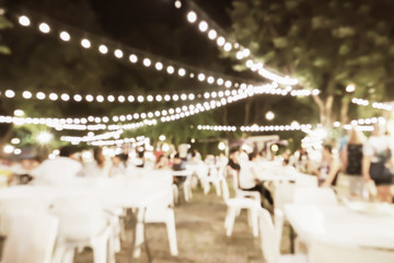 Outdoor party blurry night image background for holiday festival with beautiful bokeh light in vintage style.