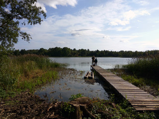 Fototapeta na wymiar lake with a bridge for fishing in the summer against a blue sky