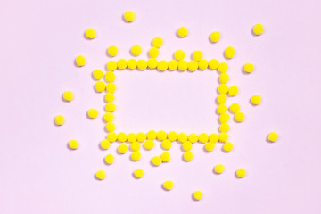 Yellow pompom polka dots frame border on pastel pink background