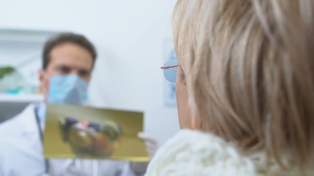 Male dietitian showing female patient picture with fruits, healthy diet