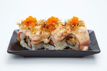 Japanese sushi rolls served on stone slate on white background.