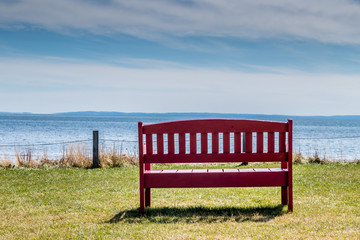 A red park bench at Point Prim Light House Museum in PEI, Canada