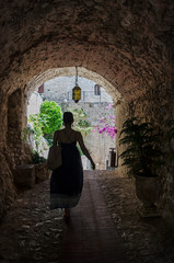 Woman Walking through a Stone Archway 