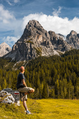 Naklejka na ściany i meble Adventure Man sSitting on Rock after Solo Hiking Dolomites Mountains