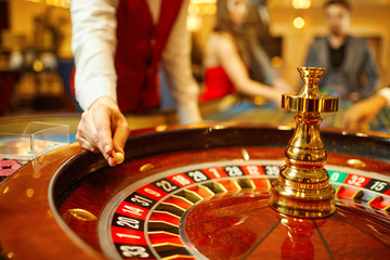 The croupier holds a roulette ball in a casino in his hand.