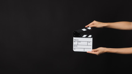 Hand is holding small white clap board or movie slate. It is use in video production , movie ,film, cinema industry on black background.