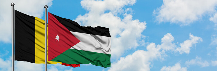 Belgium and Jordan flag waving in the wind against white cloudy blue sky together. Diplomacy concept, international relations.
