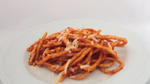 1flying over a plate of bucatini amatriciana with a drop of pecorino cheese