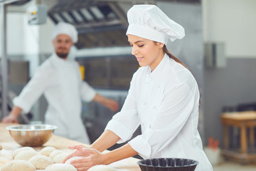 A girl baker smiles with colleagues at a bakery.