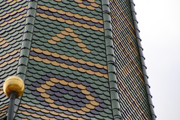 Details eines bunt gedeckten Kirchturms in Bayern