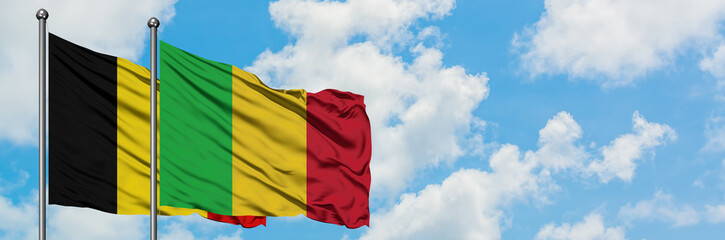 Obraz premium Belgium and Mali flag waving in the wind against white cloudy blue sky together. Diplomacy concept, international relations.