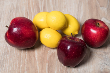 Lemons and red apples studio image. Red apples with lemon on a wooden background. Sweet apple and sour lemon.
