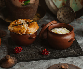portioned shash pilaf and rice in two pottery pans on stone board