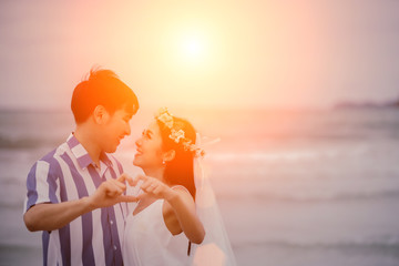 Valentine day, Young couple make heart-shaped hands with kissing in the background.