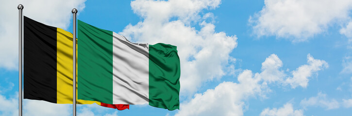 Belgium and Nigeria flag waving in the wind against white cloudy blue sky together. Diplomacy concept, international relations.