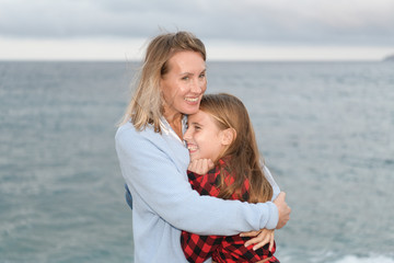 Mother and daughter hugged and happy show their affection next to the sea