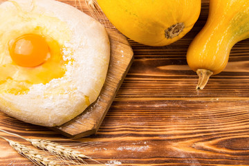 Home kitchen. Billet for baking on a wooden background. Near yellow pumpkins and ears of wheat. Copy space