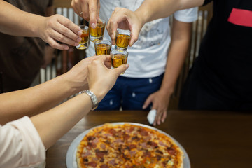 Friend with rum shots on party with pizza on table.