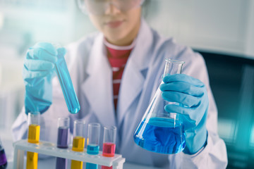 Fototapeta premium Young Asian medical technologist female making testing with test tube while doing research in science laboratory