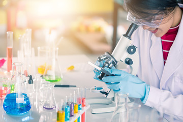 Fototapeta premium Young Asian medical technologist female making testing with test tube while doing research in science laboratory