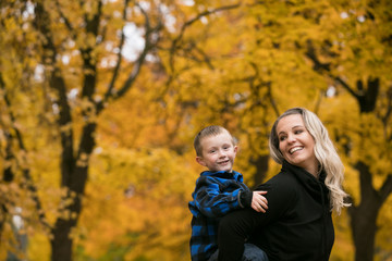 Cute mother and son piggy back in autumn color