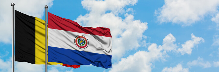 Belgium and Paraguay flag waving in the wind against white cloudy blue sky together. Diplomacy concept, international relations.