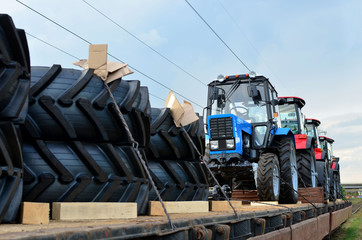 Farm tractors loaded on a freight train. Import/export of the agriculture and farming equipment....