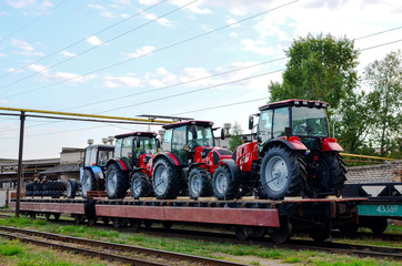 Farm tractors loaded on a freight train. Import/export of the agriculture and farming equipment. Logistics transportation agricultural tractors by rail. Customs control zone, multimodal transportation