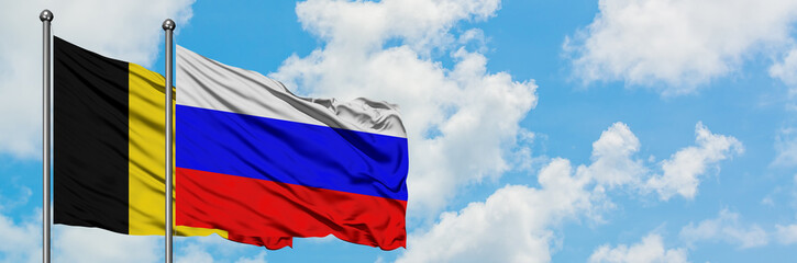 Belgium and Russia flag waving in the wind against white cloudy blue sky together. Diplomacy concept, international relations.