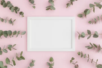 Crédence de cuisine en verre imprimé Rose clair Top view of a white frame mockup surrounded by branches of eucalyptus on a pink background.
