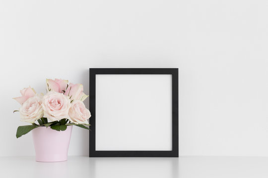 Black square frame mockup with pink roses in a pot on a white table.