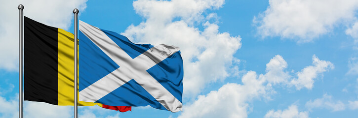 Belgium and Scotland flag waving in the wind against white cloudy blue sky together. Diplomacy concept, international relations.