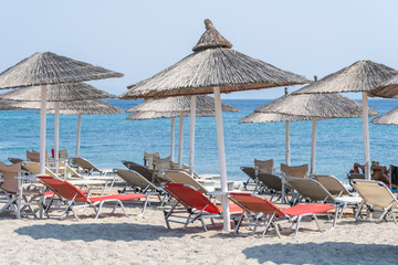 Sun beds and umbrellas on beach by the sea water, Greece