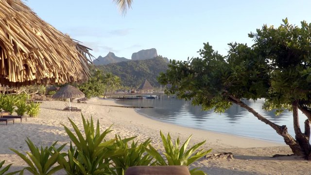 SEAMLESS LOOP VIDEO: Beach on Bora Bora vacation paradise island with overwater bungalows resort hotel and beach hut in coral reef lagoon ocean and beach. Mount Otemanu, Bora Bora, Tahiti.