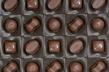 Brown chocolate candy background. Assortment of chocolate candies sweets in the box