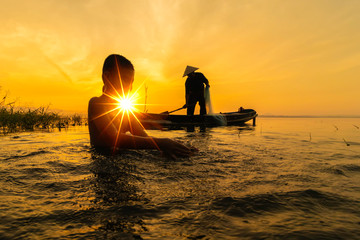 Children fishermen still cast fishing villages.Son fishing swimming and fishing equipment. happy the smiles of the children.The fishermen will cast On the old wooden boat A beautiful morning sunrise.